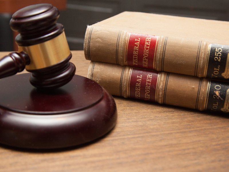 Judge's gavel in a courtroom with a stack of law books