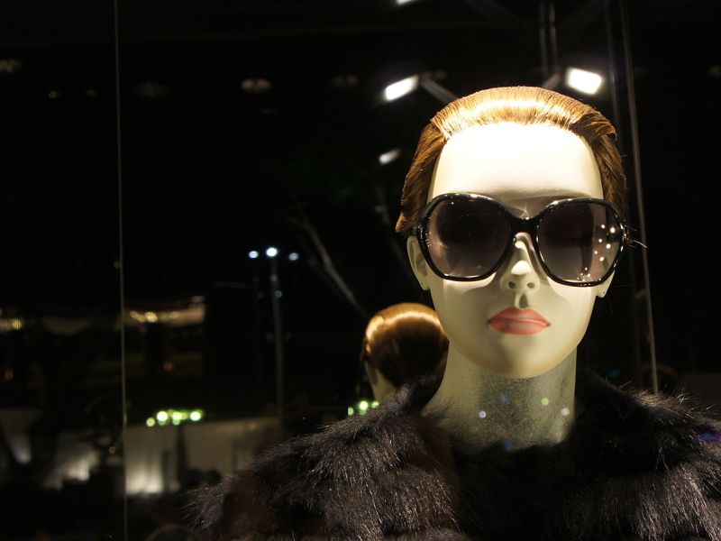Female mannequin with black fur and sunglasses.